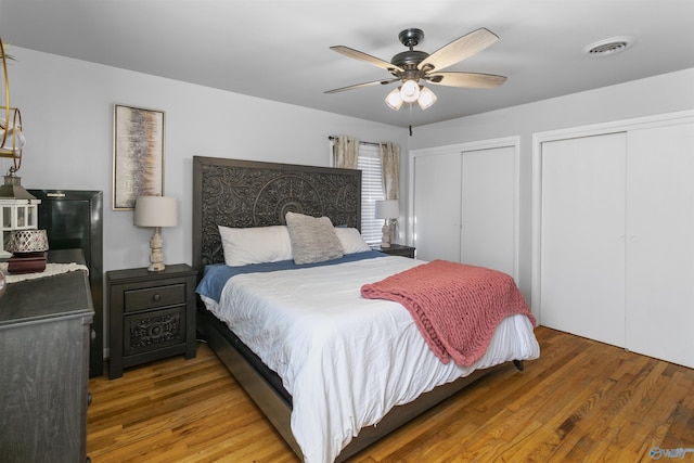 bedroom featuring multiple closets, ceiling fan, and hardwood / wood-style floors