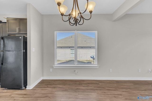 unfurnished dining area featuring hardwood / wood-style floors, a notable chandelier, plenty of natural light, and beamed ceiling