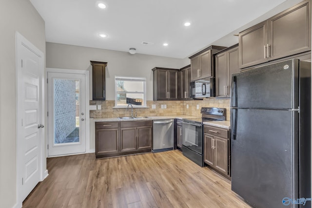 kitchen featuring sink, backsplash, black appliances, dark brown cabinets, and light wood-type flooring