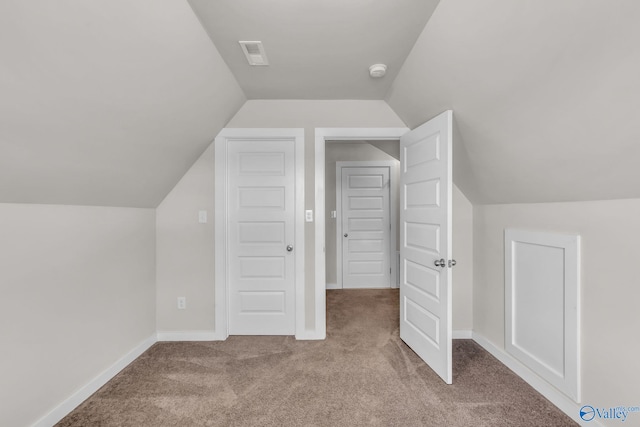 bonus room with light colored carpet and vaulted ceiling