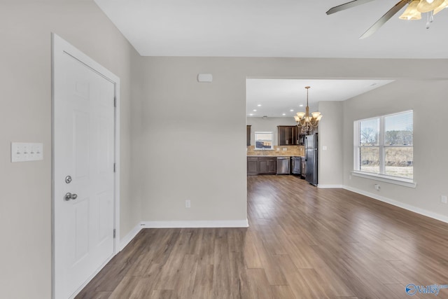 interior space with wood-type flooring and ceiling fan with notable chandelier