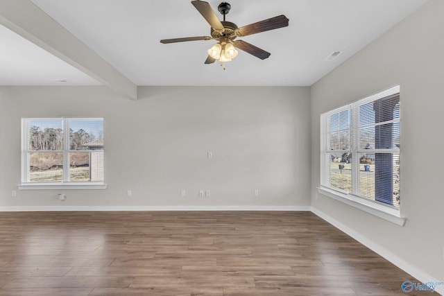 spare room featuring beamed ceiling, ceiling fan, plenty of natural light, and hardwood / wood-style floors