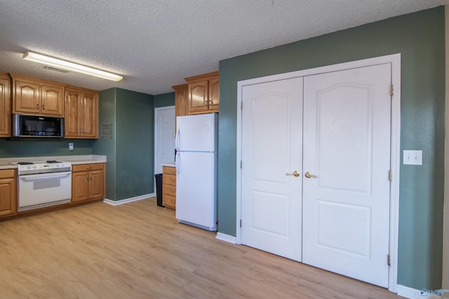 kitchen featuring a textured ceiling, white appliances, and light hardwood / wood-style flooring