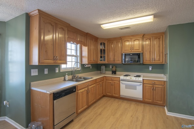 kitchen featuring white range with electric stovetop, sink, stainless steel dishwasher, light hardwood / wood-style floors, and a textured ceiling