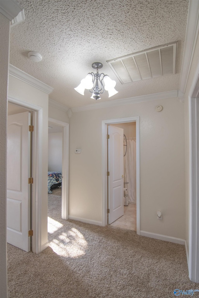 corridor featuring crown molding, light carpet, a textured ceiling, and an inviting chandelier