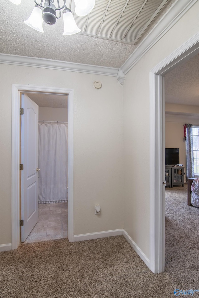 corridor featuring ornamental molding, light carpet, and a textured ceiling