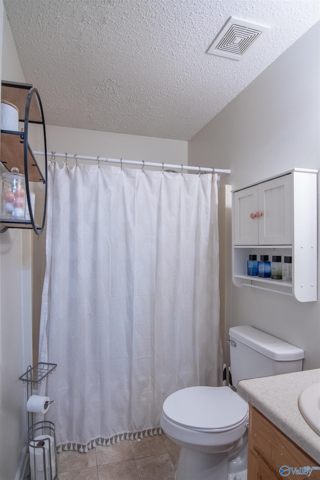 bathroom with vanity, toilet, tile patterned flooring, and a textured ceiling