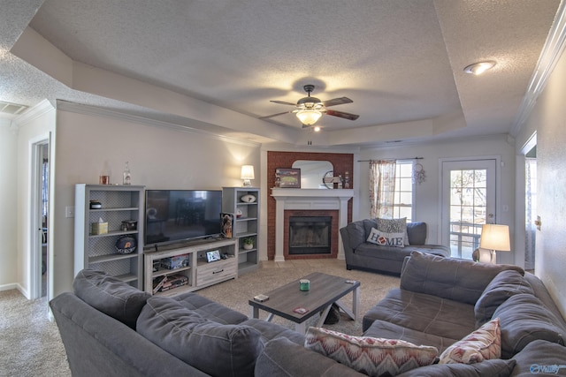 living room featuring a fireplace, carpet floors, ornamental molding, a textured ceiling, and a raised ceiling