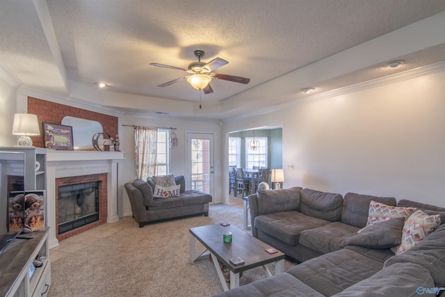 living room with ornamental molding, a fireplace, a raised ceiling, and a textured ceiling