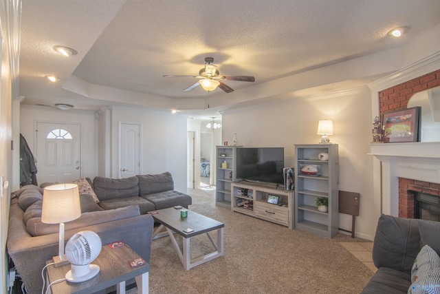 carpeted living room with ceiling fan, a tray ceiling, a fireplace, and a textured ceiling