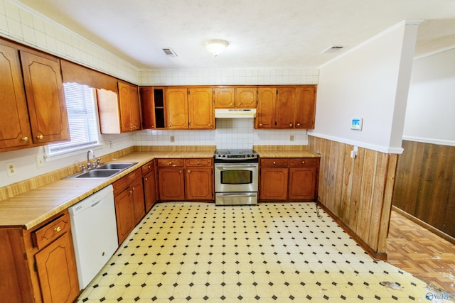 kitchen with wood walls, sink, ornamental molding, white dishwasher, and electric stove