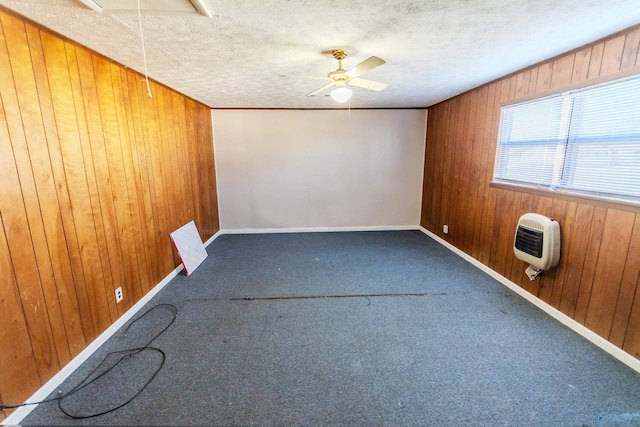 unfurnished room with carpet, heating unit, a textured ceiling, and wooden walls