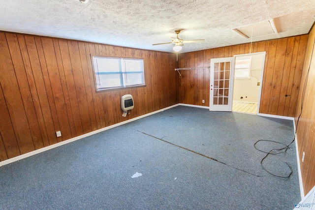 empty room featuring ceiling fan, wood walls, heating unit, and a textured ceiling