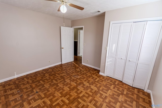 unfurnished bedroom featuring dark parquet flooring, ceiling fan, a textured ceiling, and a closet