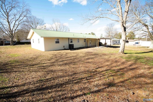 rear view of property with central AC unit and a yard