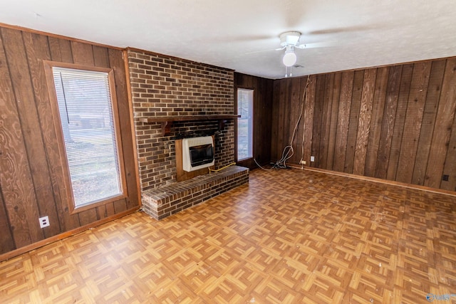 unfurnished living room featuring a fireplace, light parquet floors, heating unit, and wood walls