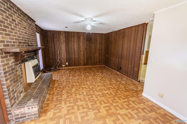 unfurnished living room with heating unit, a fireplace, wooden walls, ceiling fan, and light parquet flooring