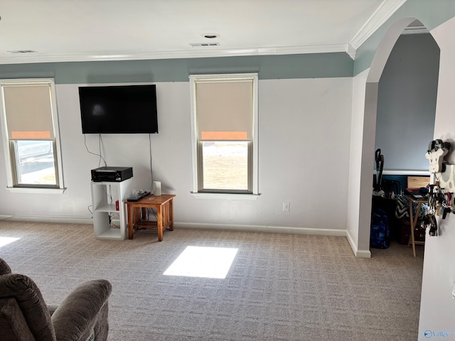 living area featuring a wealth of natural light, crown molding, arched walkways, and carpet flooring