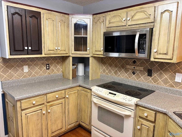 kitchen featuring white electric range, stainless steel microwave, backsplash, and glass insert cabinets