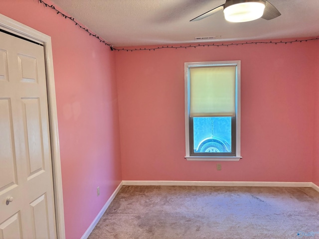 spare room with carpet floors, a textured ceiling, baseboards, and a ceiling fan