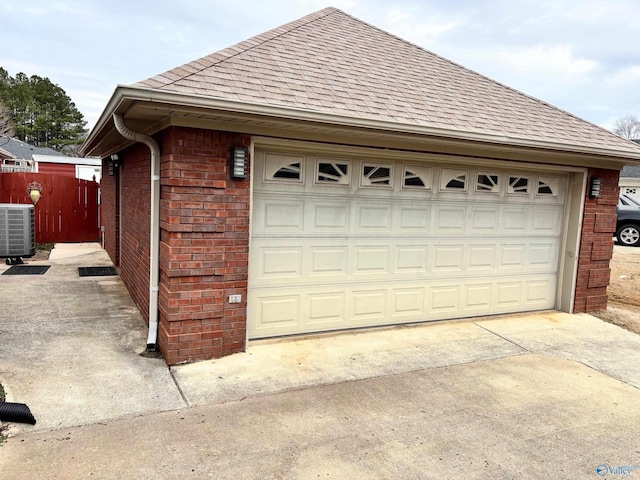 detached garage featuring fence and central AC unit