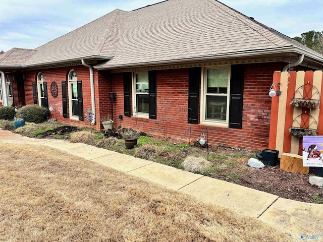 view of front of home with roof with shingles and brick siding