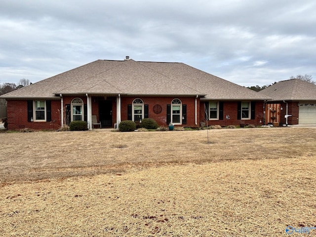 ranch-style home featuring an attached garage, brick siding, and a shingled roof