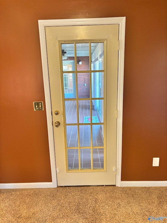 doorway featuring baseboards and carpet flooring