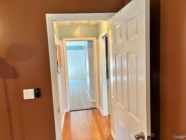 hallway featuring light wood-style floors and baseboards