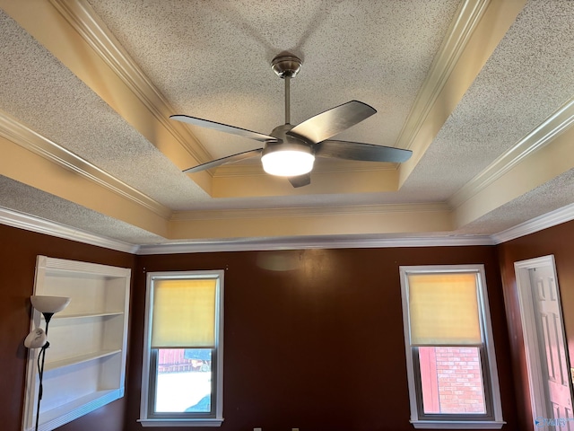 interior details with a ceiling fan, a tray ceiling, a textured ceiling, and ornamental molding