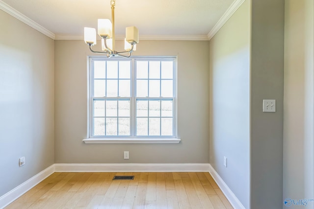 unfurnished room featuring an inviting chandelier, hardwood / wood-style flooring, and crown molding