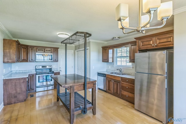 kitchen with sink, stainless steel appliances, light stone countertops, crown molding, and light hardwood / wood-style floors