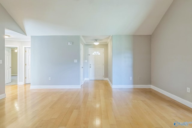 empty room featuring light wood-type flooring and vaulted ceiling