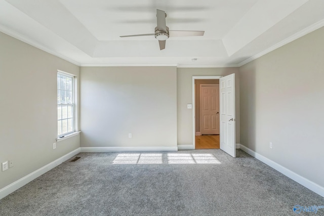 spare room featuring ceiling fan, light colored carpet, a tray ceiling, and crown molding