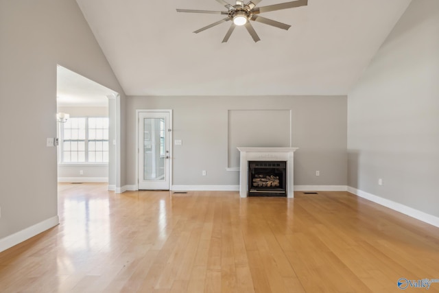 unfurnished living room featuring ceiling fan with notable chandelier, light wood-type flooring, and vaulted ceiling