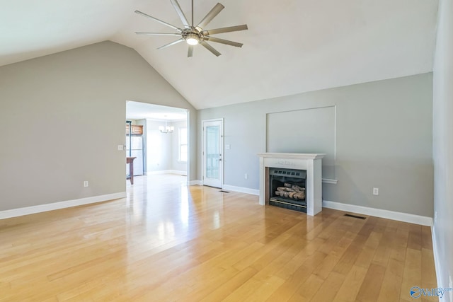 unfurnished living room featuring ceiling fan with notable chandelier, light wood-type flooring, and lofted ceiling