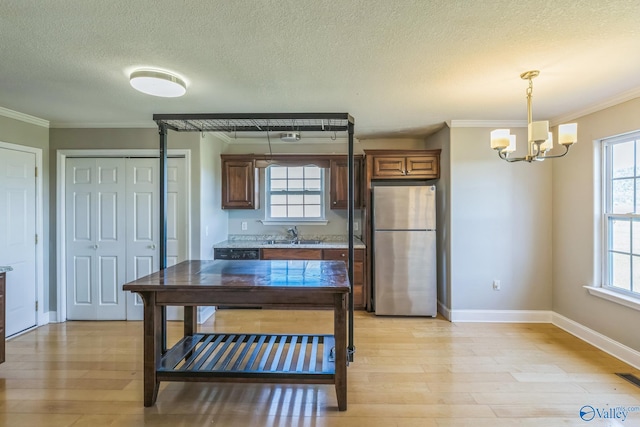 kitchen with pendant lighting, light wood-type flooring, a chandelier, stainless steel refrigerator, and ornamental molding