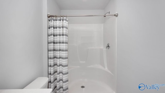 bathroom with curtained shower and toilet