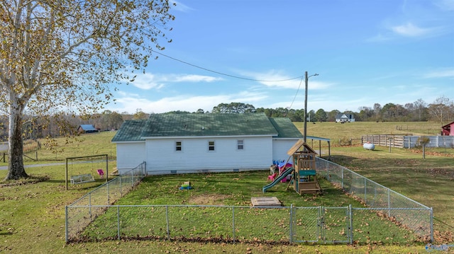 rear view of property with a playground and a yard