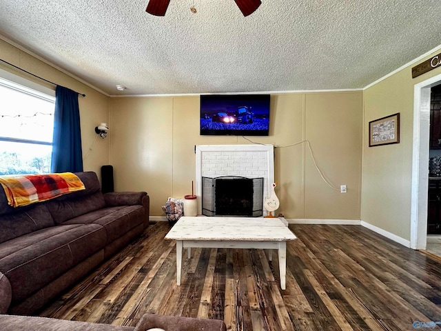 living room featuring ornamental molding, a textured ceiling, ceiling fan, dark wood-type flooring, and a fireplace