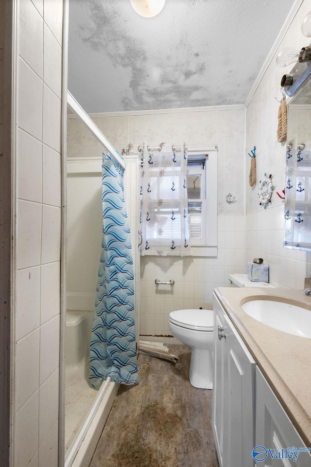 bathroom with toilet, a shower with curtain, a textured ceiling, tile walls, and vanity