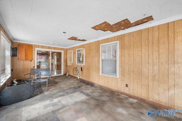 interior space with wooden walls, ornamental molding, and concrete flooring