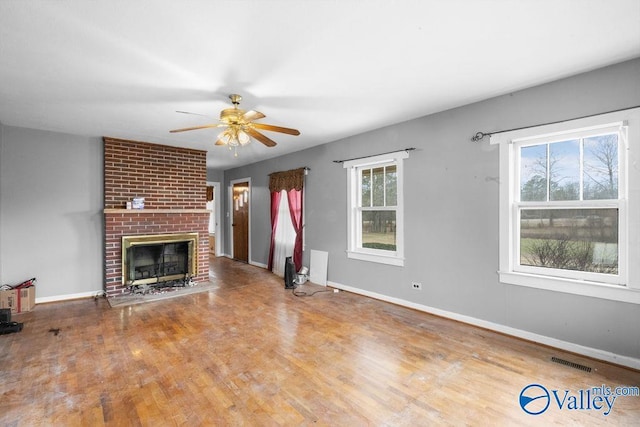 unfurnished living room with hardwood / wood-style floors, a fireplace, and ceiling fan