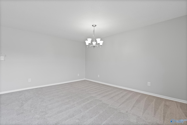 carpeted empty room with a notable chandelier