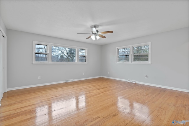 empty room featuring ceiling fan, light hardwood / wood-style floors, and a wealth of natural light