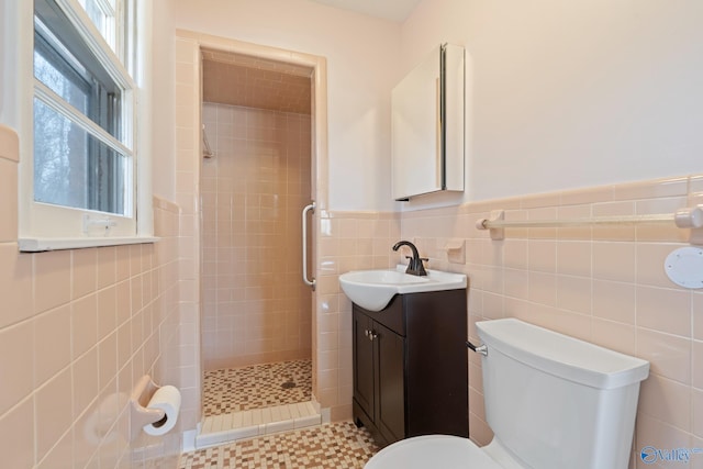 bathroom featuring tiled shower, vanity, toilet, and a wealth of natural light