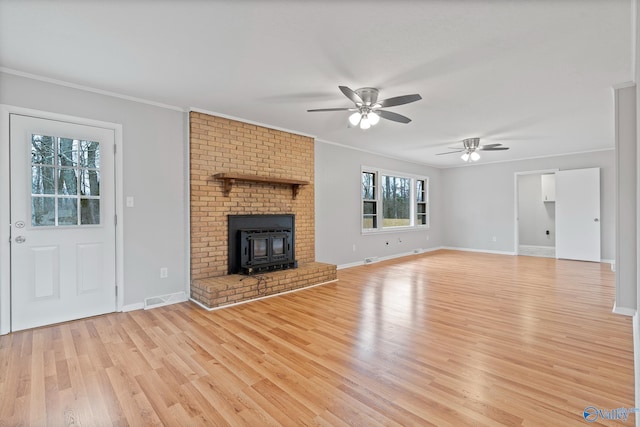 unfurnished living room featuring ornamental molding, plenty of natural light, a wood stove, and ceiling fan