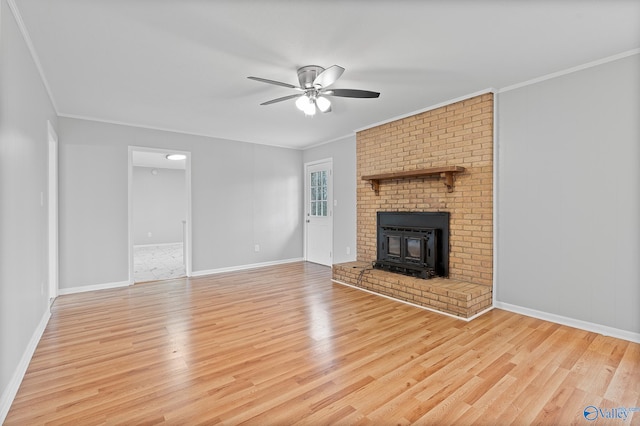 unfurnished living room with ornamental molding, a wood stove, ceiling fan, and light wood-type flooring