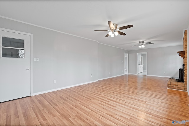 unfurnished living room featuring a fireplace, ornamental molding, ceiling fan, and light wood-type flooring