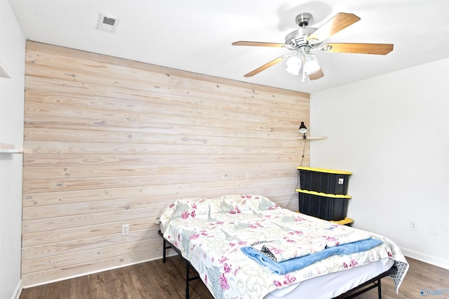 bedroom with hardwood / wood-style floors, ceiling fan, and wood walls